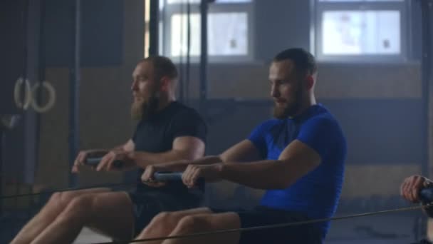 Entrenamiento de amigos de fitness en la máquina de ergómetro fila en el gimnasio cruzado — Vídeos de Stock