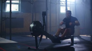Spor salonunda kürek çekiyordum. Kürek çekme makinesi kullanan genç bir adam. yavaş çekim.