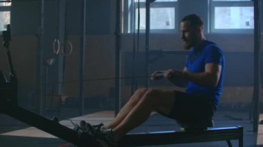 Spor salonunda kürek çekiyordum. Kürek çekme makinesi kullanan genç bir adam. yavaş çekim.