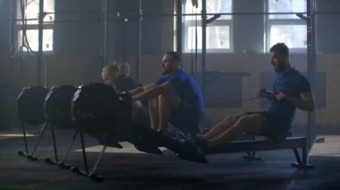 Takım çalışması. Grup kardiyo eğitimi. Fitness erkek arkadaşları çapraz spor salonunda ergometre makinesinde antrenman yapıyorlar