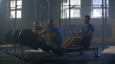 Ağır çekim: Çapraz spor salonundaki sıra ergometre makinesinde antrenman yapan spor arkadaşları