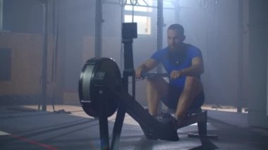 Spor salonunda kürek çekiyordum. Kürek çekme makinesi kullanan genç bir adam. yavaş çekim.