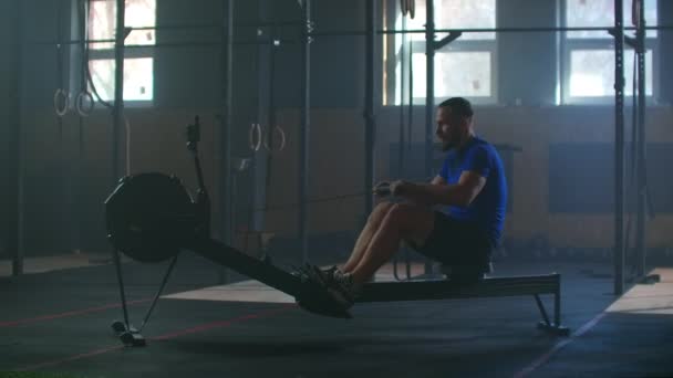 Fitness man atleet training roeitrainer oefening intense uithoudingsvermogen workout uitdaging sterke sportman lichamelijke oefening in de sportschool gezonde levensstijl motivatie close-up handen. slow motion — Stockvideo