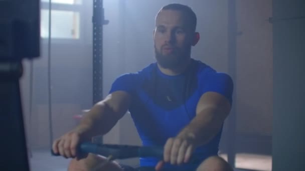 Fitness man idrottare träning roddmaskin motion intensiv uthållighet träning utmana stark idrottsman fysisk träning i gym hälsosam livsstil motivation närbild händer. slow motion — Stockvideo