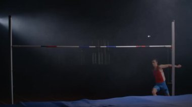 Erkek bir atlet koşuyor ve direğin üzerinden atlıyor. Yüksek atlama yarışmasında yavaş çekim. Profesyonel Olimpiyat sporları