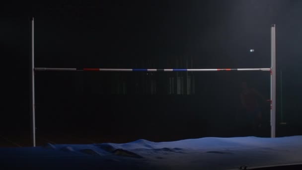 남자 운동 선수가 크로스바 위로 뛰고 높이 뛰어 오릅니다. 하이 점프 대회의 느린 모션 사격. 성공 — 비디오