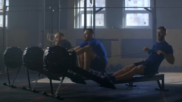 Drei Männer trainieren gemeinsam auf Rudergeräten in Zeitlupe. Teamtraining — Stockvideo