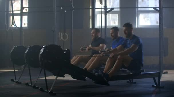 Estilo de vida activo y saludable, jóvenes atléticos hombres caucásicos felices hacen ejercicio juntos en las máquinas de gimnasio de remo cámara lenta — Vídeo de stock