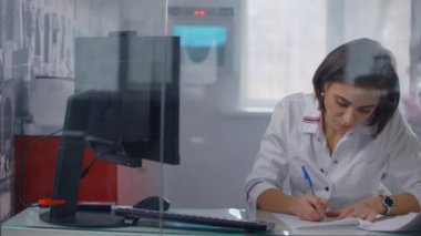 Kadın doktor bazı evrakları dolduruyor. Kağıda yazı yazan birinin yakın çekimi. Belgelerin ne olduğunu doldur. Plastik cerrah