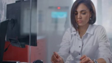 Yoğun bir hastanede bilgisayar üzerinde çalışan modern, yakışıklı bir kadın doktorun yakın çekimi..