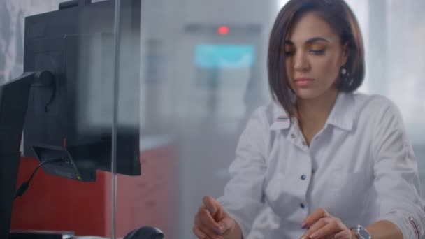 Close-up of a modern handsome female doctor working on a computer in a busy hospital. — Stock video