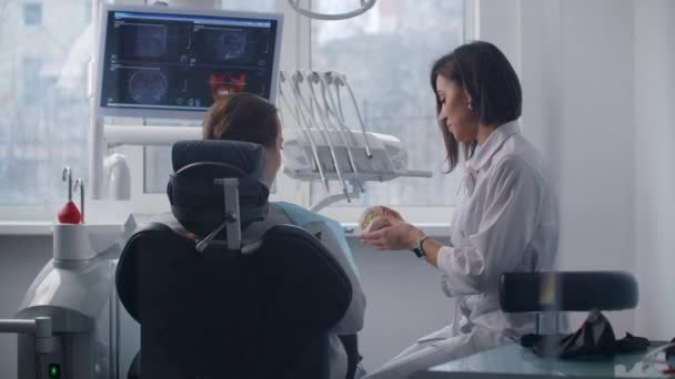 De orthodontist bespreekt de oplossing van de patiëntenproblemen en het algoritme van de tandheelkundige behandeling. Gezonde en mooie glimlach — Stockvideo