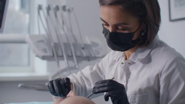 Dentista que realiza cirurgia com equipamento esterilizado. Retrato de um dentista. O paciente na cadeira dentária. Conceito de assistência odontológica — Vídeo de Stock