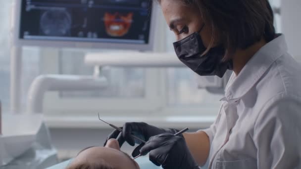 Стоматолог виконує операцію з використанням стерилізованого обладнання. Портрет стоматолога. Пацієнт у стоматологічному кріслі. Концепція стоматологічної допомоги — стокове відео