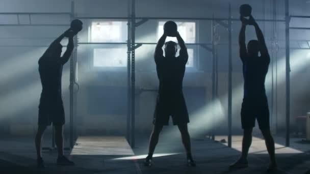 Three athletes in an atmospheric fitness room against the background of sunlight lift weights — Stock Video