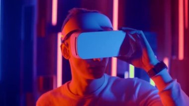 Fütüristik sanal gerçeklik, kasklı ve neon ışıklı bir adam ellerini sanal gerçeklikte hareket ettiriyor.