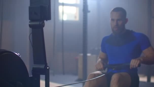Slow motion: One men rower trains in a fitness room on a rowing machine — Stockvideo