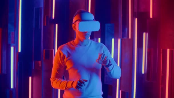 Realtà virtuale futuristica, un uomo in casco e luce al neon muove le mani mentre nella realtà virtuale — Video Stock