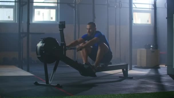 Slow motion: Rower trains, cardio athlete training. One man in an atmospheric fitness room in the sunlight in a rowing machine. — Stock video