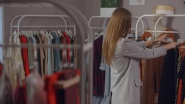 Güzel bir kadın markalı bir galeride kıyafet seçer.