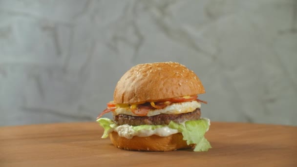 Una gran hamburguesa sabrosa con carne empanada cebolla verduras lechuga queso derretido . — Vídeos de Stock