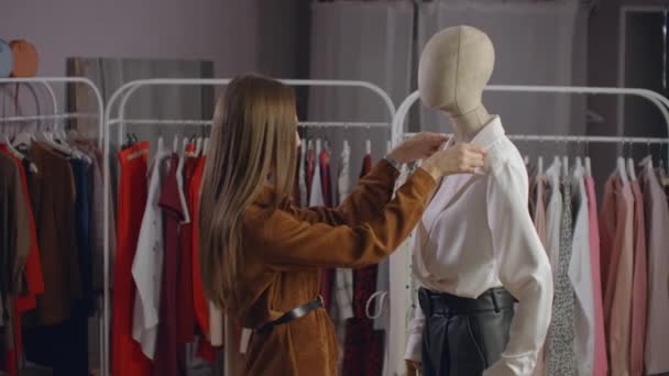 Una mujer hermosa elige la ropa en una sala de exposición de ropa de marca — Vídeo de stock