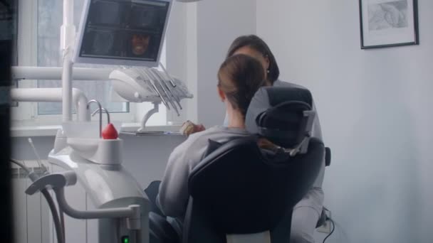 Concept de médecine, de dentisterie et de soins de santé : une dentiste discute avec une patiente du traitement dentaire au cabinet d'une clinique dentaire . — Video