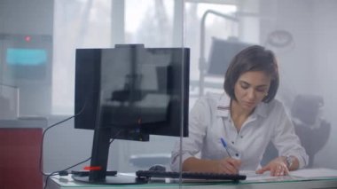 Kadın doktor bir reçete yazıyor bir tıp ofisinde bir masada tıbbi geçmişi doldurur. Uluslararası Doktorlar Günü