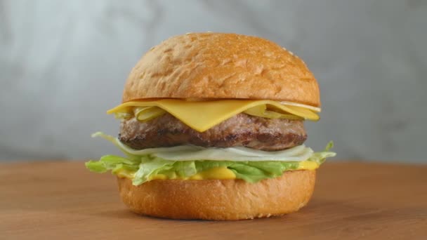 Ein großer leckerer Burger mit Fleisch Patty Zwiebeln Gemüse geschmolzener Käsesalat. — Stockvideo