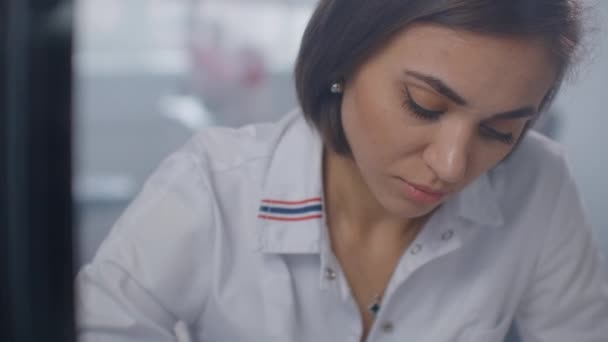 Doctor writing a prescription at desk in his cabinet — Stock Video