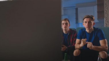 Yakın planda mutlu, etnik çeşitliliğe sahip genç arkadaşlar birlikte maç izlemeyi, zaferi evde kutlamayı seviyorlar. Eğlence konsepti.