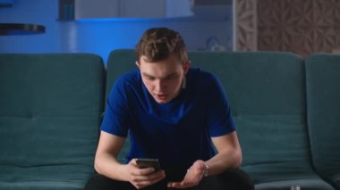 Genç mutlu hokey fanatiği bahis kazanıp akıllı telefon izliyor. Adam kumar mobil uygulaması ile bahsi kazandı..