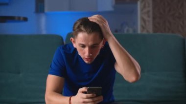 Genç mutlu futbol fanatiği bahis kazanıp akıllı telefon izliyor. Kumar mobil uygulaması ile bahsi kazanan adam kutluyor. Futbol bahsi