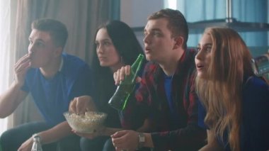 Yakın planda mutlu, etnik çeşitliliğe sahip genç arkadaşlar birlikte maç izlemeyi, zaferi evde kutlamayı seviyorlar. Eğlence konsepti.