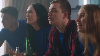 Arkadaşlar TV 'yi spor müsabakalarıyla izlerler ve başarıdan sonra kutlama yaparlar ve birlikte duygusal olarak bağırırlar ve bira ve patlamış mısırla sarılırlar.