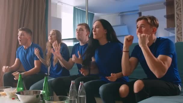 Grupa radosnych przyjaciół oglądających mecz piłki nożnej i świętujących zwycięstwo w domu — Wideo stockowe