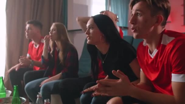 Dos amigas y tres amigas miran fútbol en casa. Su equipo favorito gana, la compañía es feliz, grita y abraza todos juntos . — Vídeos de Stock