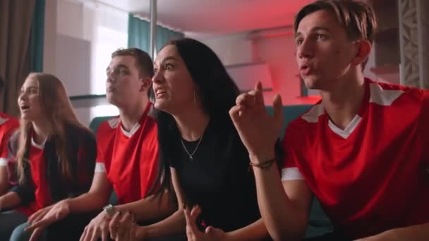 Grupo de fãs estão assistindo a um momento de futebol na TV e comemorando um gol, sentados no sofá na sala de estar — Vídeo de Stock