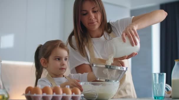 Kvinna och flicka morrande ägg på köket. Dotter och mor lagar mat tillsammans — Stockvideo