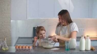 Anne ve kızı kevaşenin içine un ekiyorlar. Anne kızına hamur yoğurmayı öğretiyor. Kızına odaklan..