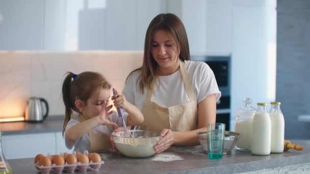 Biała matka i córka dobrze się bawią robiąc ciasto w kuchni. Szczęśliwa rodzina w kuchni. Córka dziecko przygotowuje ciasto, piec ciasteczka. — Wideo stockowe