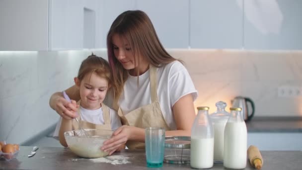 Família feliz na cozinha mãe e filha na cozinha brincando com a farinha para se divertir e moldar os rissóis na cozinha nos mesmos aventais vermelhos. estearato . — Vídeo de Stock