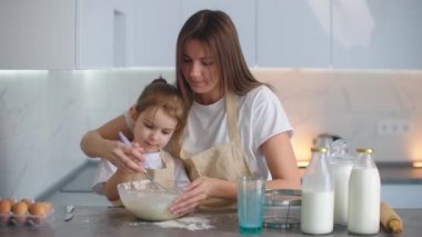 Gülen anne ve kızı mutfakta yemek pişiriyor. Kız annesinden nasıl turta yapılacağını öğreniyor. Mutlu çocukluk