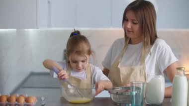 Anaokulundan bir kız evde anneme yemek pişirmede yardım ediyor. Sevgi dolu bir anne, kızına yemek pişirmeyi öğretir.