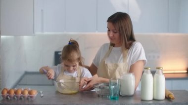 Anne ve kızı kevaşenin içine un ekiyorlar. Anne kızına hamur yoğurmayı öğretiyor. Genç anne asistanı. Ekmek ve turta üretimi için aile işi, aile pastanesi..
