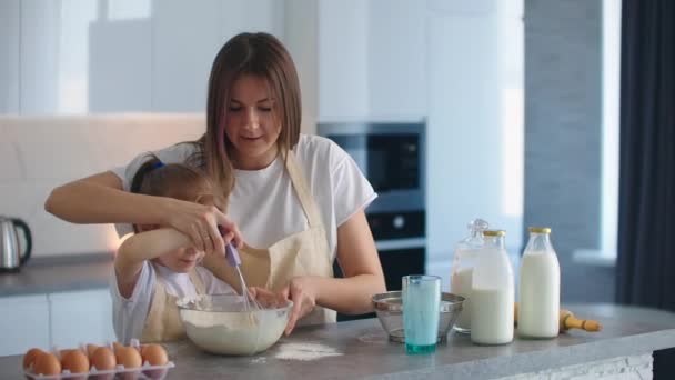Maminka učí své dospívající dceři, jak vařit těsto v kuchyni doma — Stock video