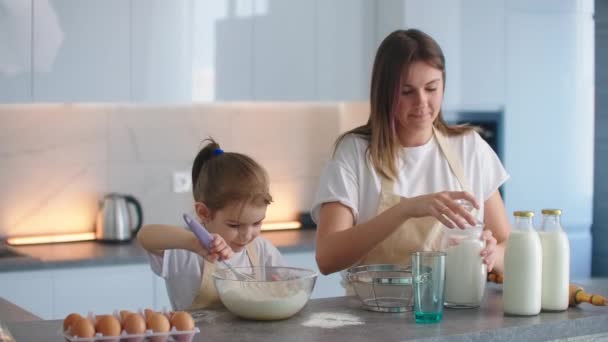 Annesi ve küçük anaokulu asistanı mutfakta birlikte yemek pişiriyorlar. — Stok video