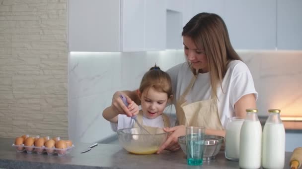 Glückliche Familie in der Küche Mutter und Tochter in der Küche spielen mit Mehl, um Spaß zu haben und die Pasteten in der Küche in den gleichen roten Schürzen formen. Stedicam. — Stockvideo