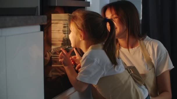 Moeder moeder en dochter kijken als een taart wordt bereid in de oven. Gelukkige jeugd. Maak samen zelfgemaakte pizza — Stockvideo