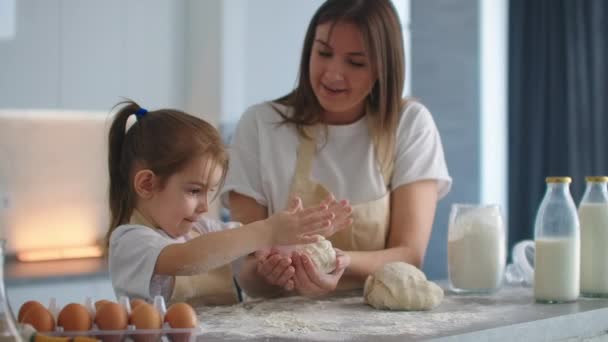 Madre enseñando a su hija a amasar masa para galletas en la cocina en cámara lenta. Mamá enseñar niño hija aprendizaje amasar masa con rodillo, niña divertida ayudar a la madre a preparar galletas . — Vídeos de Stock